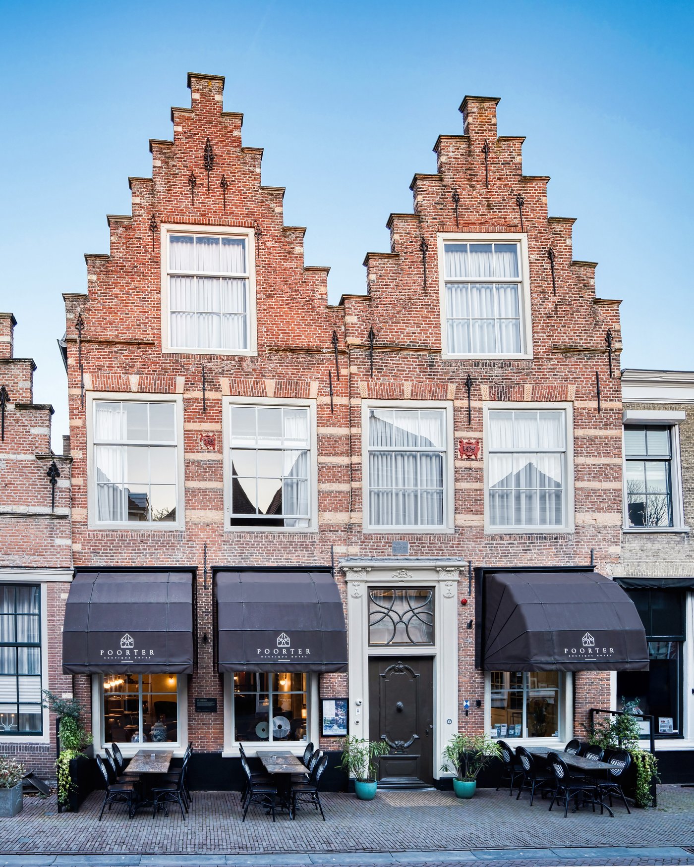 Het volledige pand van Poorter Boutique Hotel met trapgevels, entree en terras aan de Voorstraat in Brielle