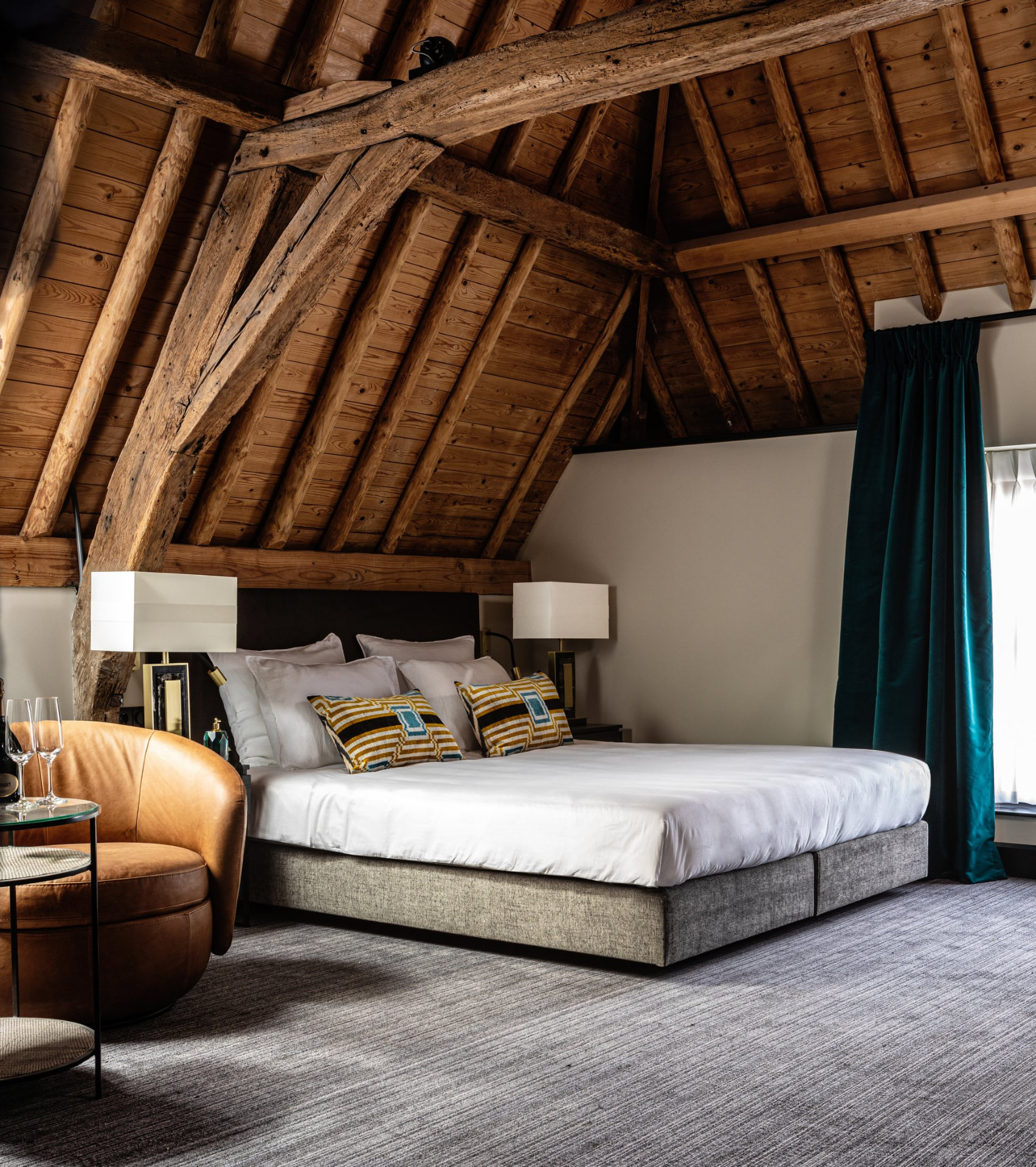 Warme hotelkamer met historische houten balken en goudkleurige details