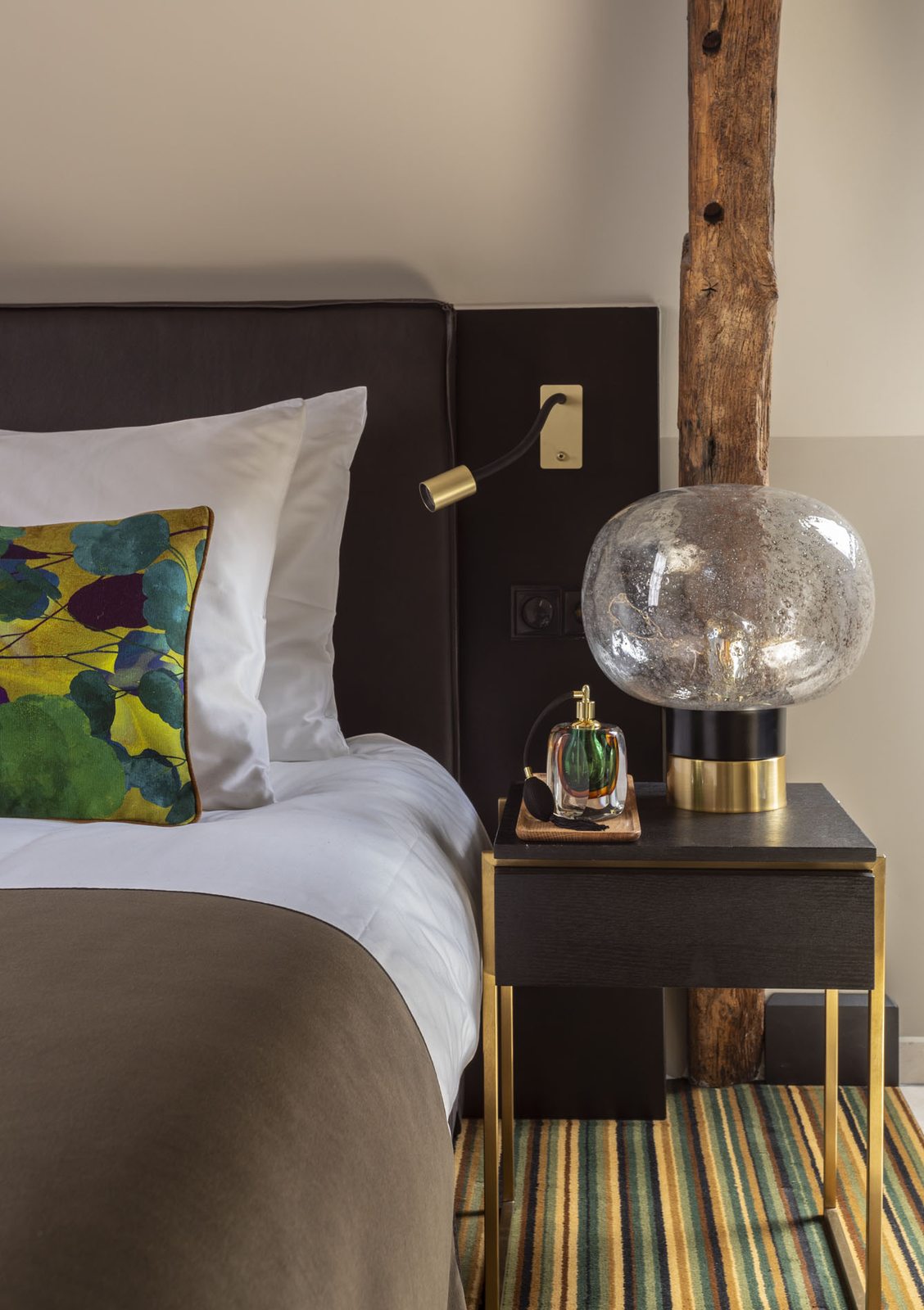 Comfy Room: detail van het bed met nachtkastje en messing leeslamp