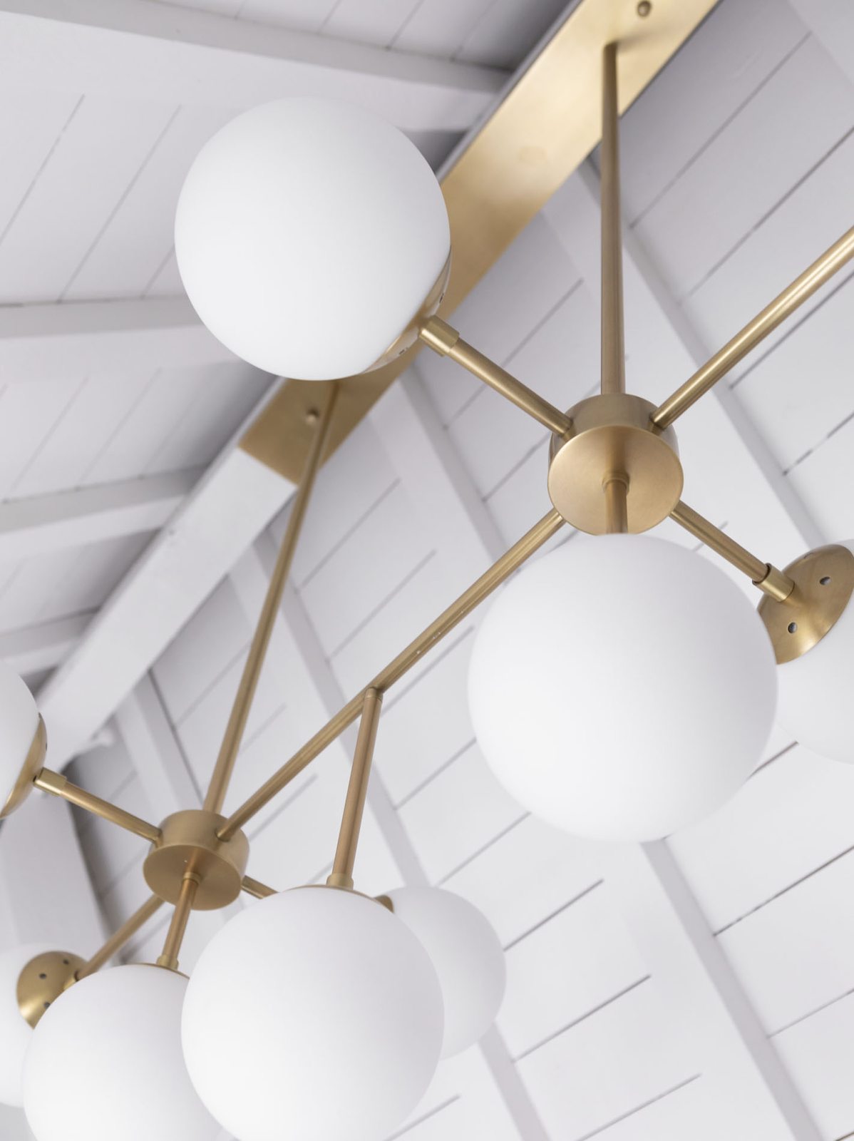 Suite: messing hanglamp met glazen bollen tegen de witte balkenkap